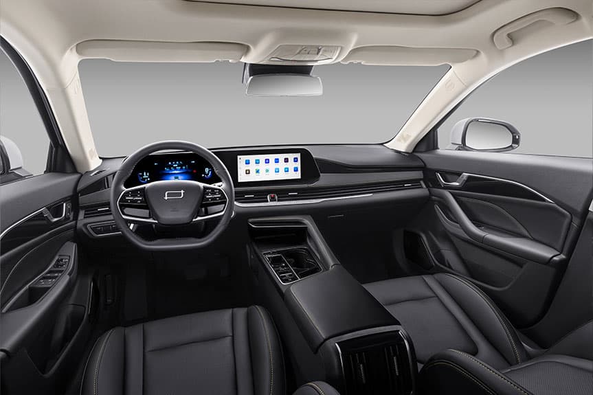 Interior de un coche moderno con asientos de cuero negro, pantalla táctil y volante multifunción.